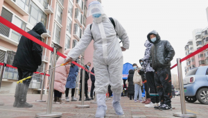 Um trabalhador desinfeta o chão enquanto os moradores aguardam o teste de Covid-19 no município de Tianjin, China