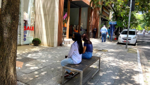 Duas jovens sentadas em um banco na rua Oscar Freire durante o dia