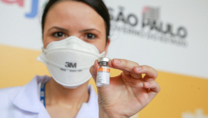 Enfermeira de máscara PFF3 mostra frasco de vacina