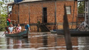 Pessoas tentam se locomover de barco durante enchente em bairro de Marabá