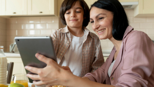 Mãe e filho olhando em um tablet na cozinha, ambos sorrindo
