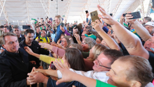 Bolsonaro é tietado por centenas de apoiadores, que levantam as mãos e apontam os celulares para o presidente