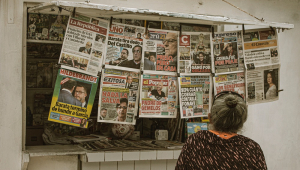 Idosa observa jornais pendurados em uma banca no Peru