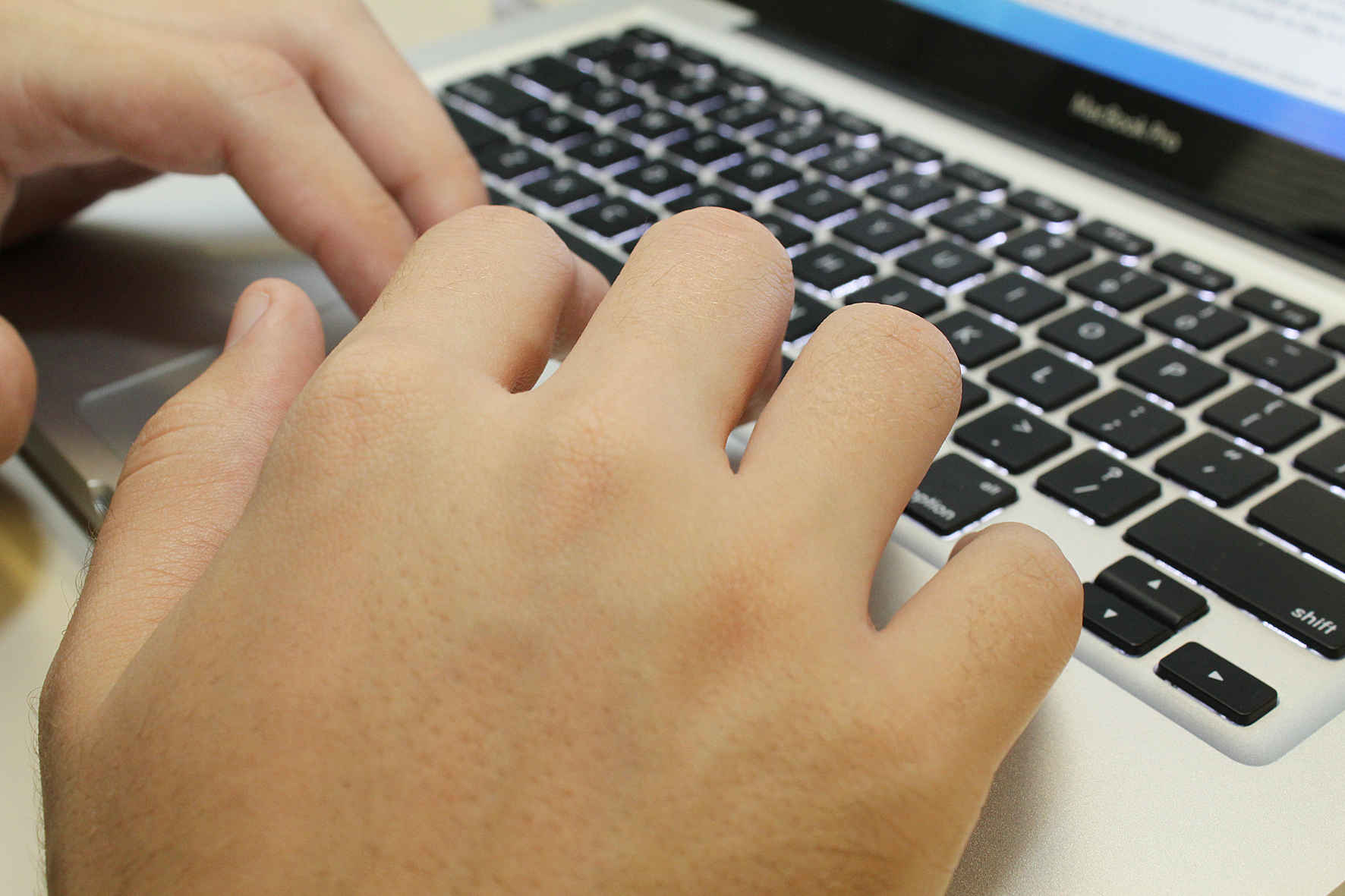 Mão digita em teclado de laptop