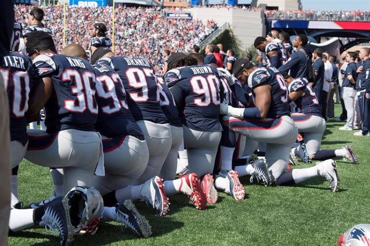 Jogadores do New England Patriots ajoelhados durante a execução do hino nacional