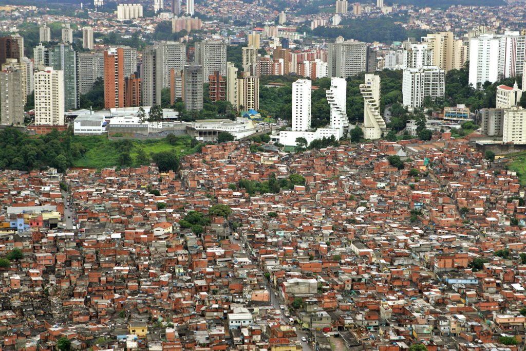 Vista de uma favela e ao lado prédios de luxo