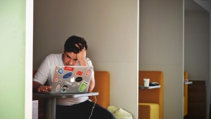 Homem com a mão na cabeça e lendo no computador com aparência de preocupado