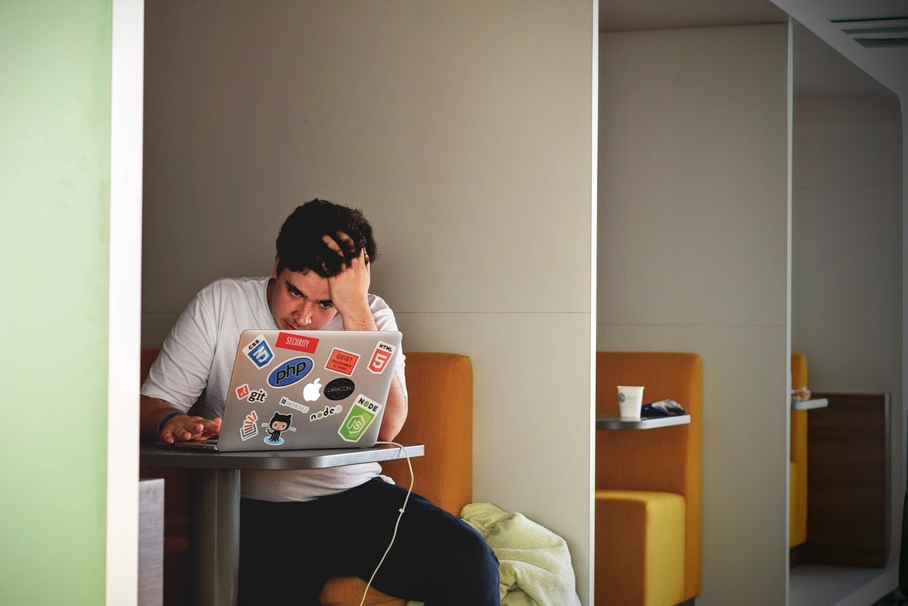 Homem com a mão na cabeça e lendo no computador com aparência de preocupado