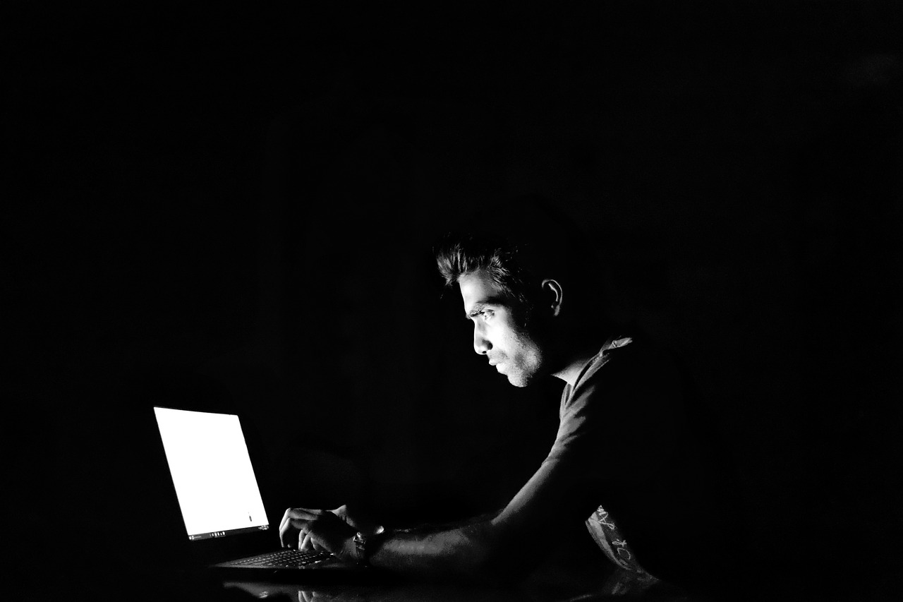 Homem navega em computador em um local escuro
