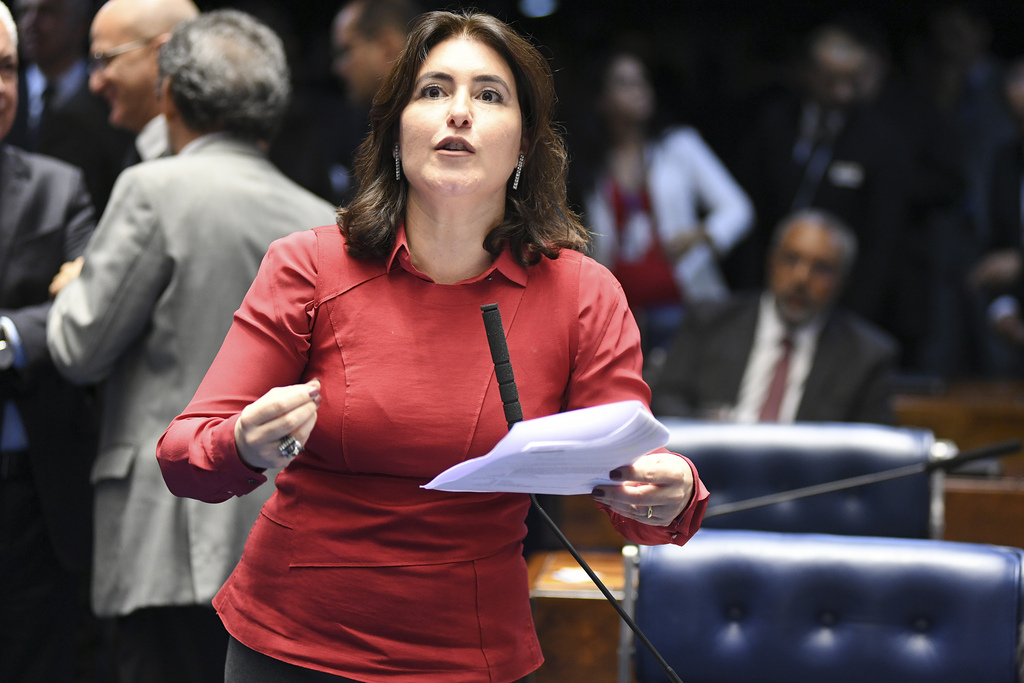 Senadora Simone Tebet segurando um papel e falando em sessão na Câmara. Usa blusa vermelha de mangas compridas e tem cabelos na altura do ombro castanhos