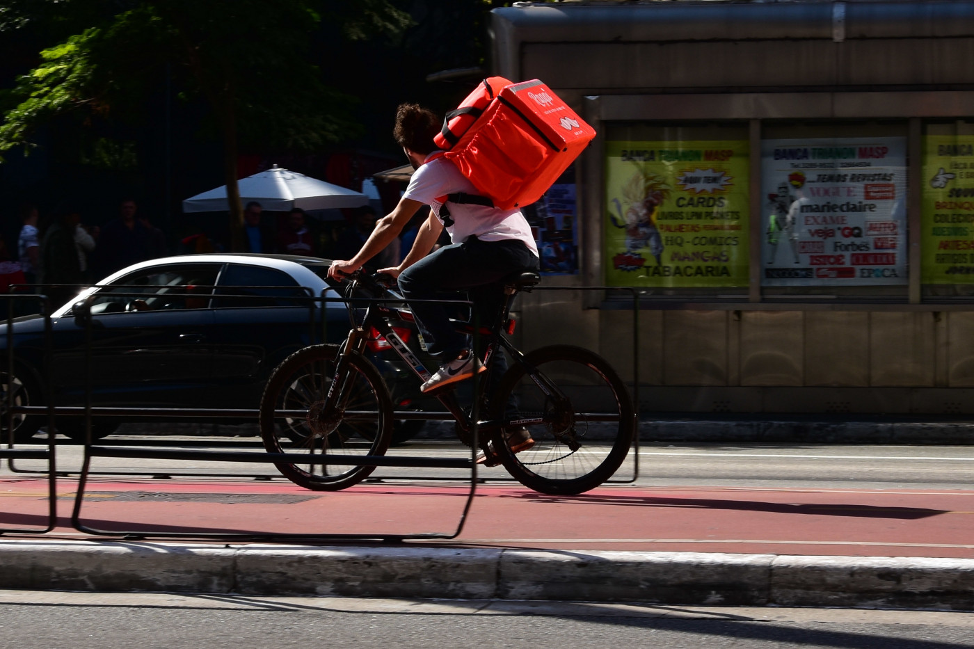Homem andando de bicicleta com uma bag laranja