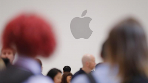 Pessoas cmainham em frente ao logotipo da Apple, uma maçã mordida