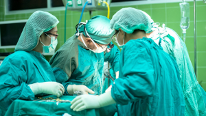 Três profissionais vestindo roupas de ala cirúrgica