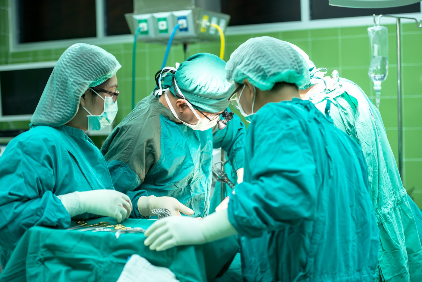 Três profissionais vestindo roupas de ala cirúrgica