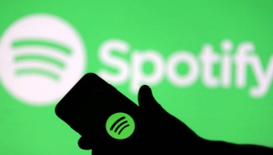 Homem segurando celular com logo do Spotify à mostra