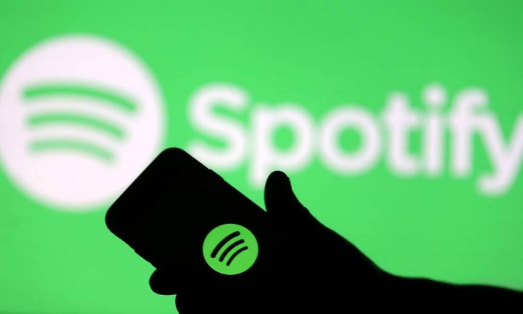 Homem segurando celular com logo do Spotify à mostra