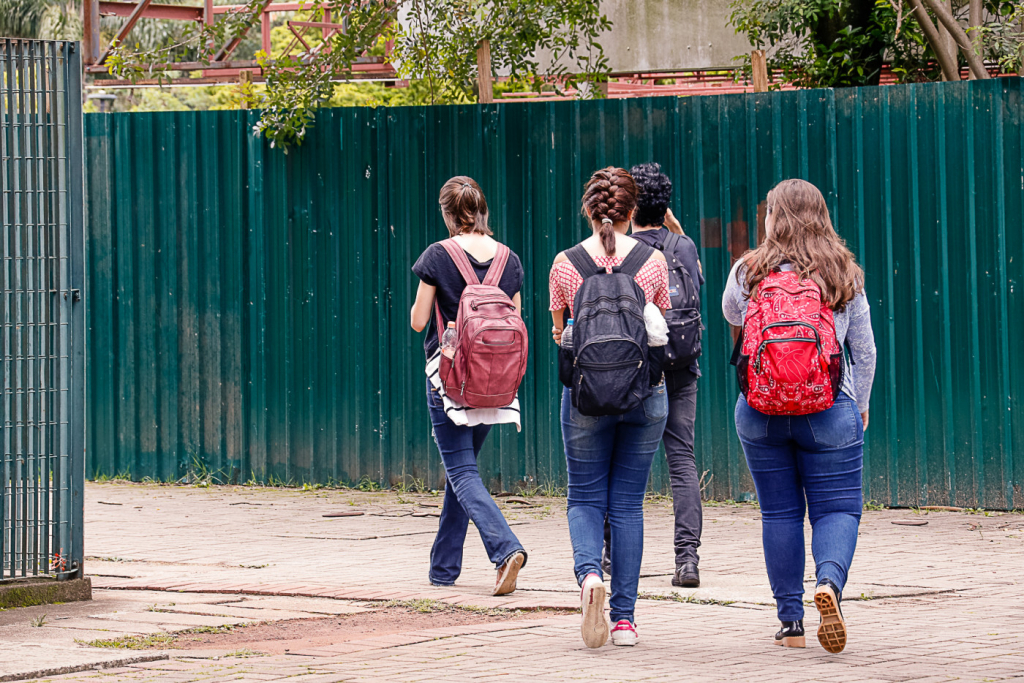 grupo de alunos caminha com mochila nas costas