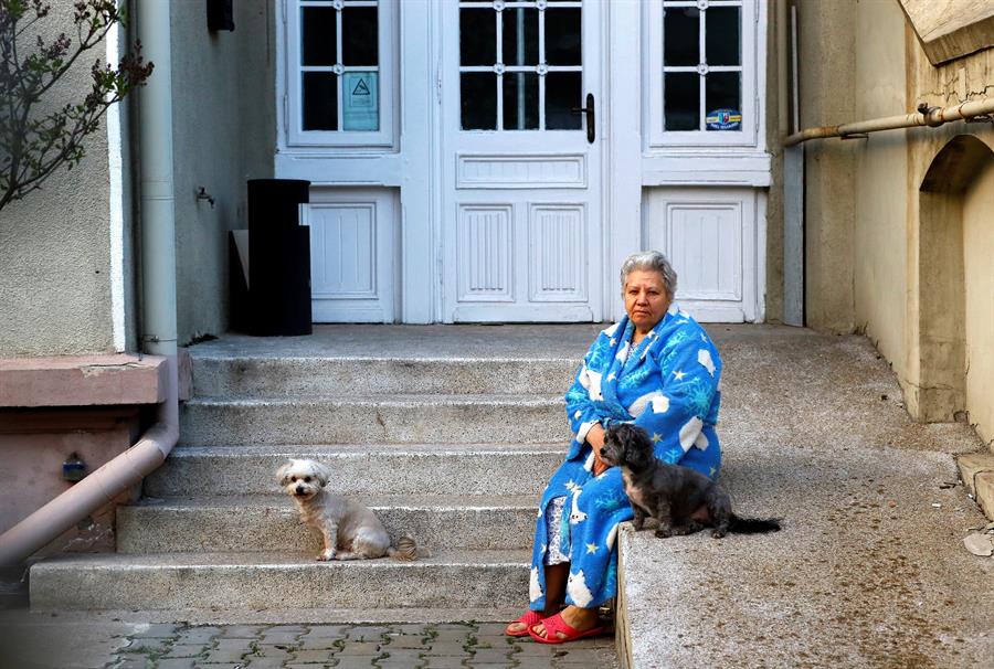 Idosa sentada na porte de casa com um cachorro