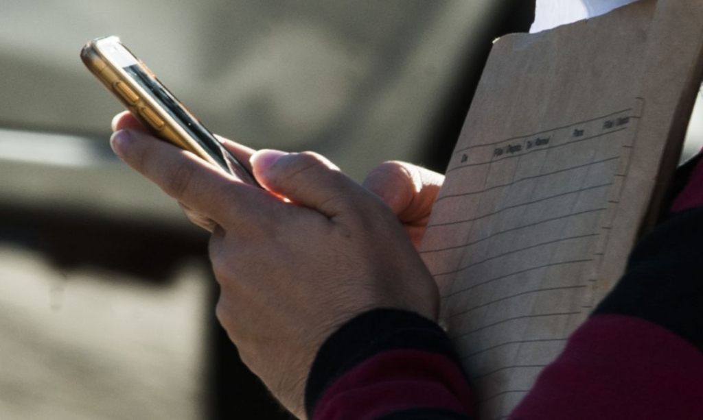 Pessoa com caderno e celular na mão