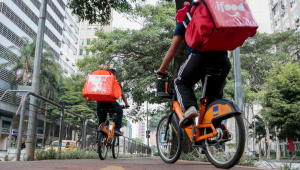 entregadores de aplicativo em cima de bicicletas laranjas do Itaú
