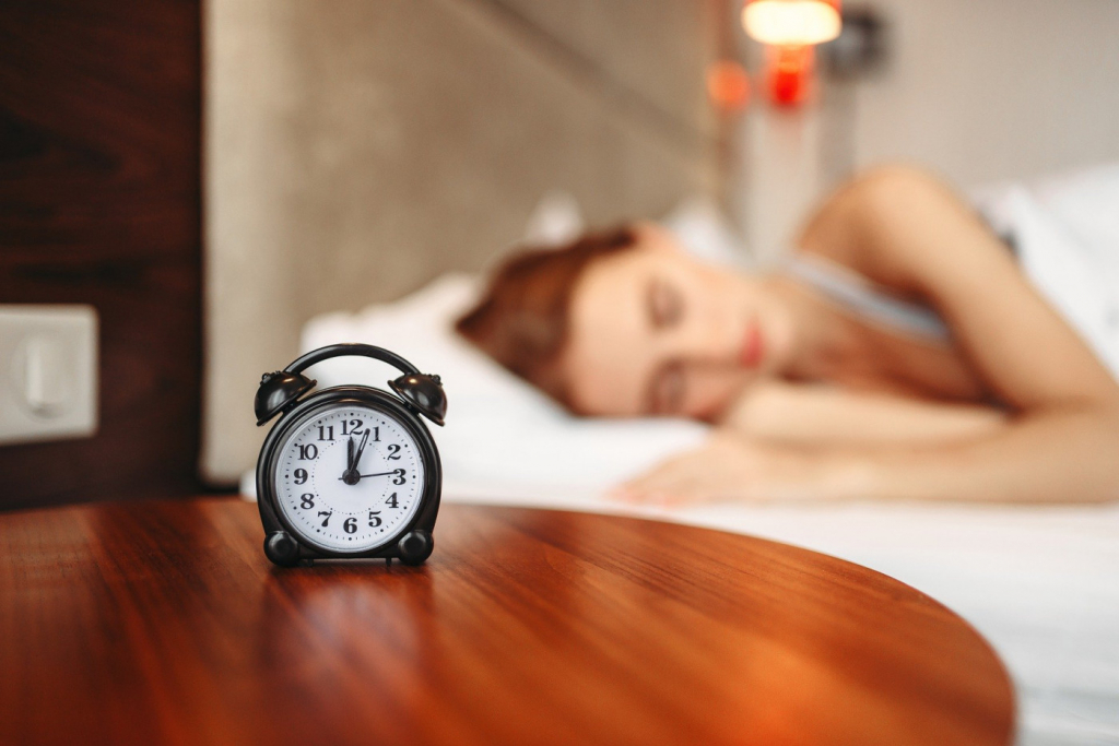 mulher dormindo com relógio em primeiro plano