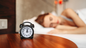 mulher dormindo com relógio em primeiro plano