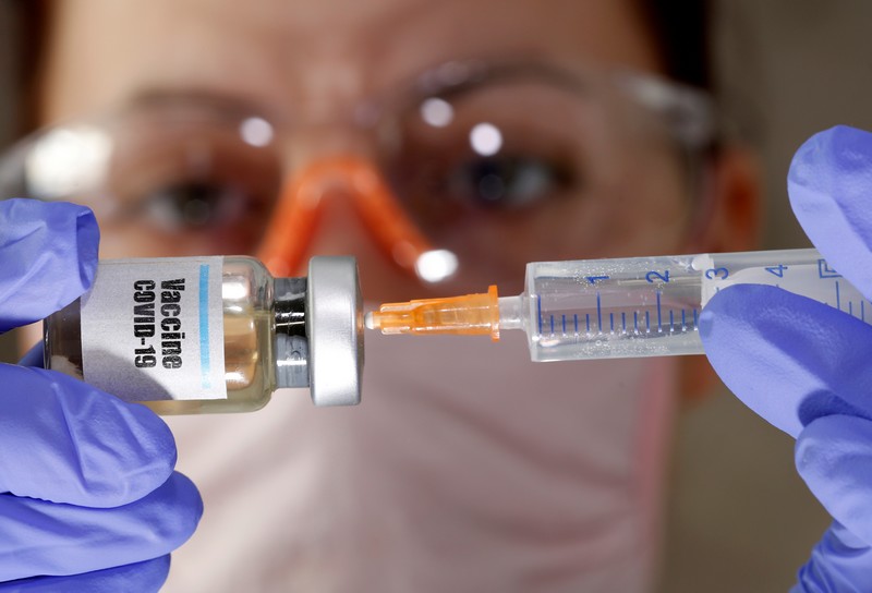 Mulher olhando frasco de vacina contra Covid