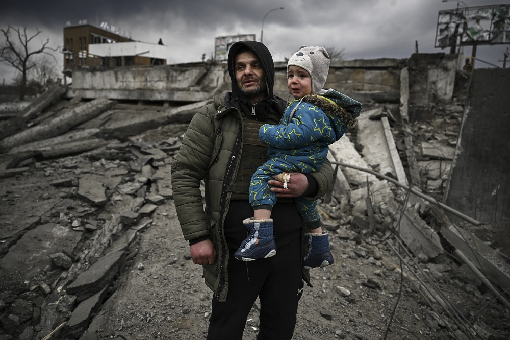 Um homem segura uma criança enquanto fugia da cidade de Irpin, a oeste de Kiev