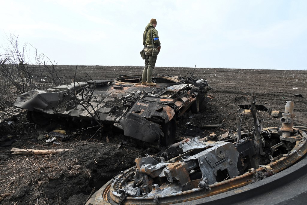 Soldado ucraniano sobre os destroços de um tanque russo queimado fora da vila de Mala Rogan, a leste de Kharkiv