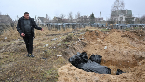 Homem gesticula para uma vala comum na cidade de Bucha, a noroeste da capital ucraniana, Kiev