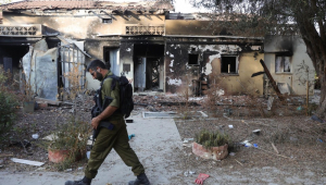 Um soldado israelense passa por uma casa em ruínas no Kibutz Beeri, perto da fronteira com Gaza