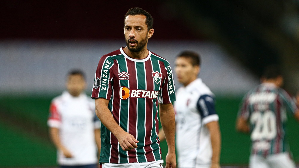 O meia Nenê , com a camisa tricolor do Fluminense, durante partida contra o Cerro Porteño; dois adversários aparecem ao fundo, desfocados