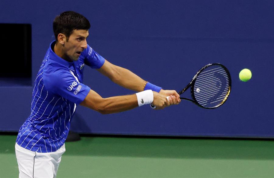 Novak Djokovic rebate uma bola durante uma partida de tênis
