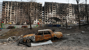 Carro queimado em frente a prédios residenciais destruídos durante conflito Ucrânia-Rússia na cidade sitiada de Mariupol, na Ucrânia