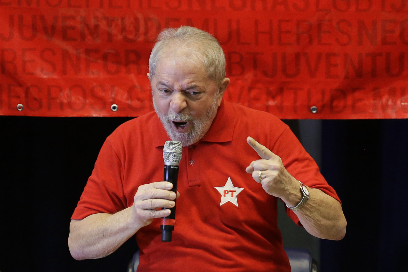 Homem de camisa vermelha com estrela do PT, cabelos grisalhos, apontando dedo e gritando