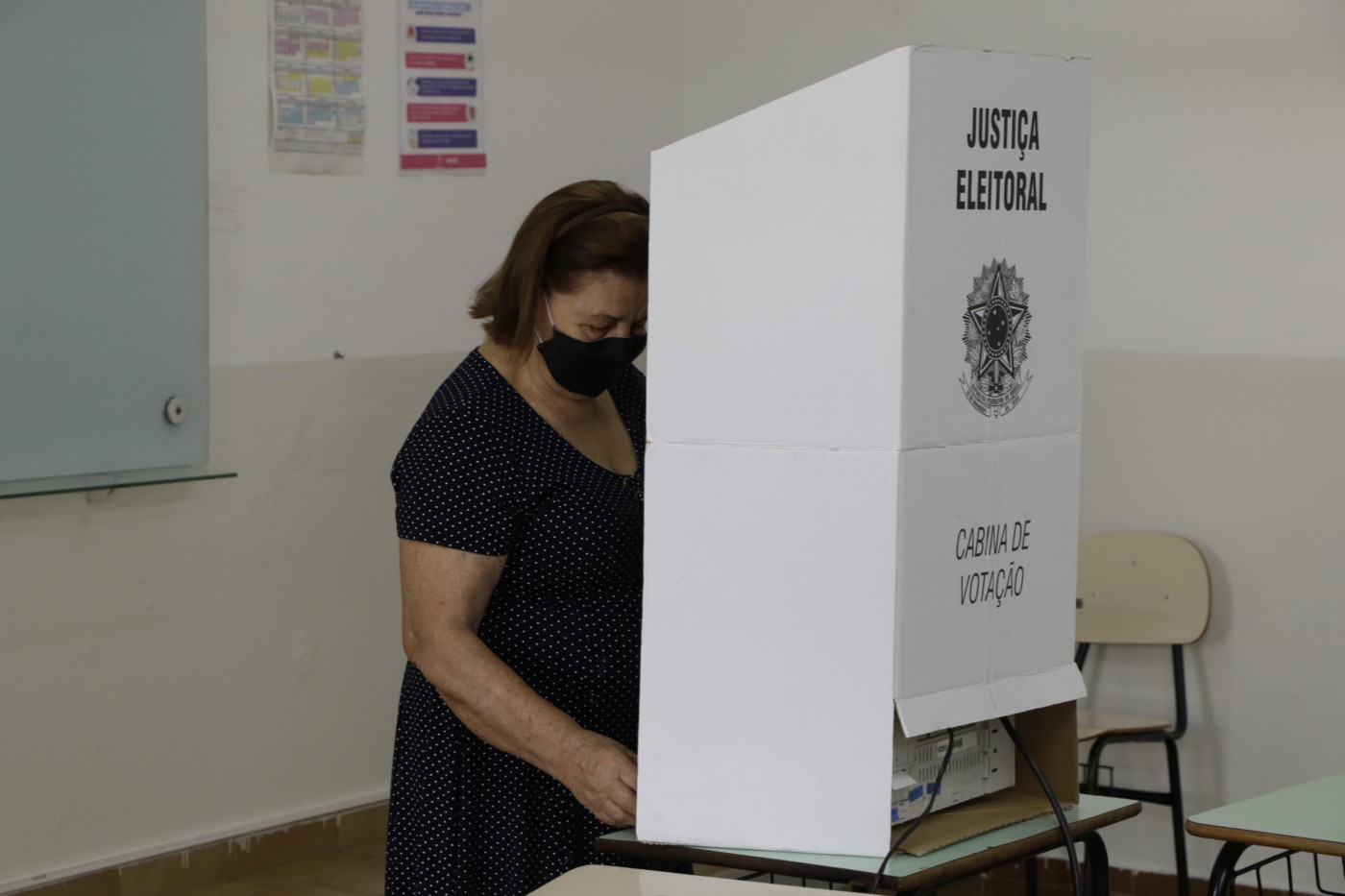 Pessoa votando de máscara em uma urna eleitoral