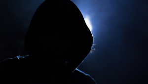 Imagem de um homem de capuz com o rosto coberto pela sombra