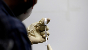 Imagem de um enfermeiro de costas colocando a dose da Covaxin em uma seringa