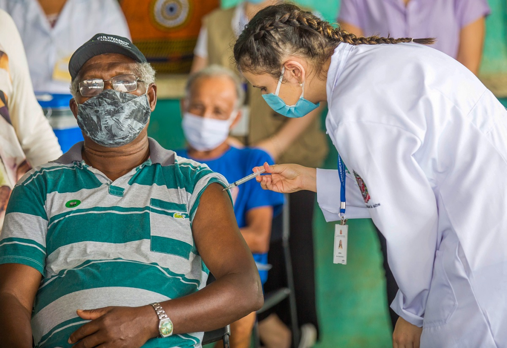 Homem de máscara recebendo vacina no braço