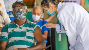 Homem de máscara recebendo vacina no braço