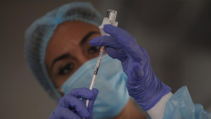 Enfermeira paramentada preenche seringa com vacina contra a Covid-19