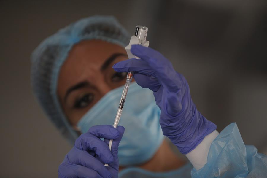 Enfermeira paramentada preenche seringa com vacina contra a Covid-19