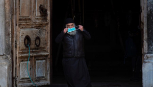 Clérigo ortodoxo deixa a Igreja do Santo Sepulcro, em Jerusalém, colocando a sua máscara
