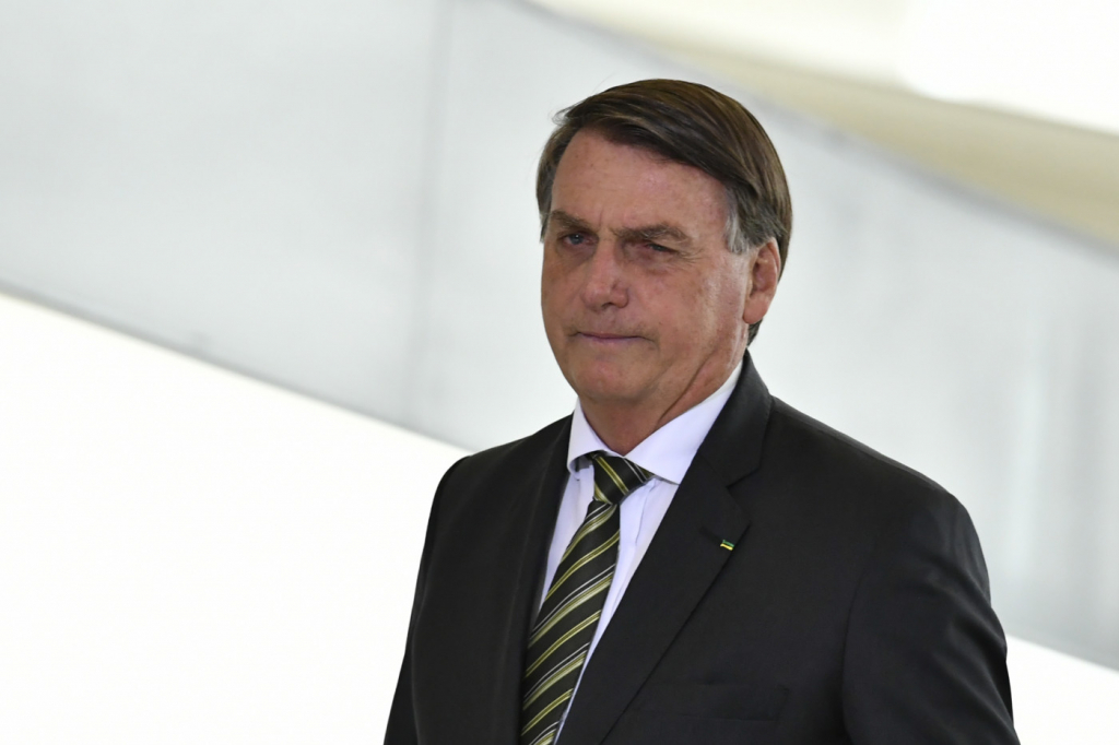 Bolsonaro de terno e gravata diante de fundo branco olhando para o horizonte