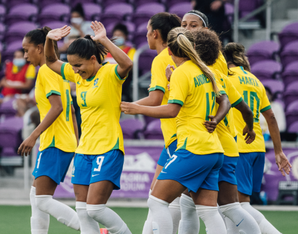 jogadoras de futebol do brasil se abraçando com uniforme do time (calção azul e camisa amarela)