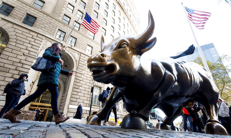 Pessoas caminham perto da estátua do touro de Wall Street, em Nova York, Estados Unidos
