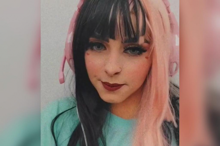 Garota de olhos claros usando fone de ouvido rosa, com cabelo liso e franja; metade do cabelo dela é rosa e a outra metade preta