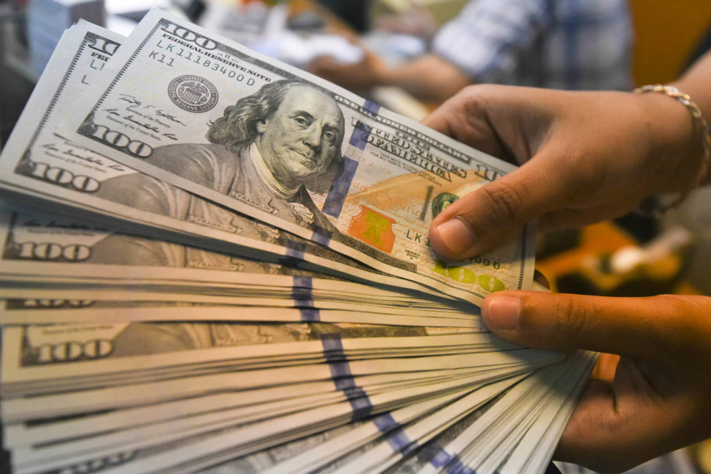 Mão segura diversas cédulas de dólar