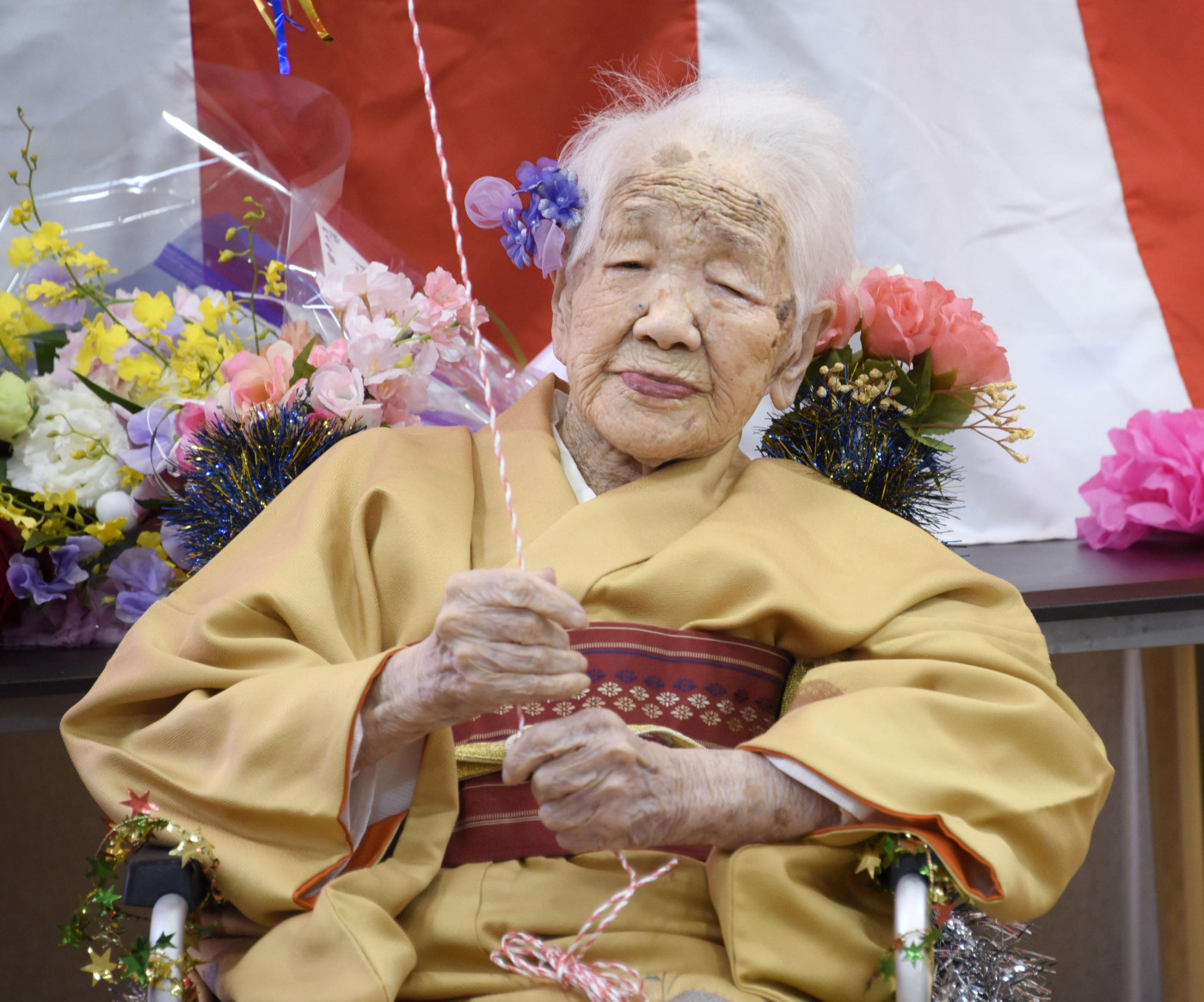 Mulher idosa de cabelos grisalhos trajando um kimono alaranjado