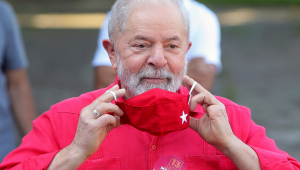 Lula segurando máscara vermelha e sorrindo